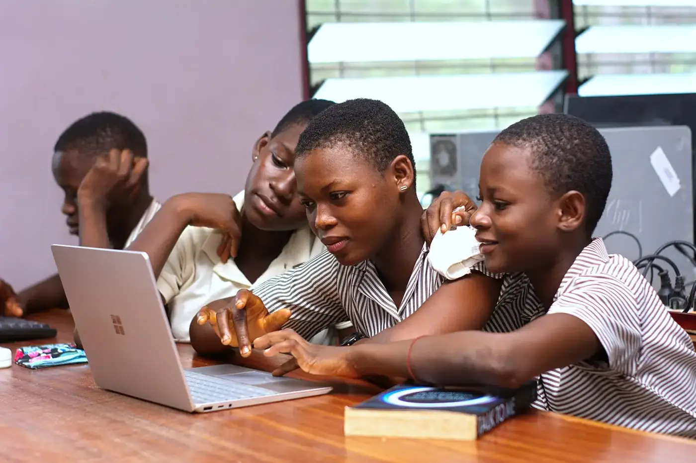 Students working together around a laptop at a desk